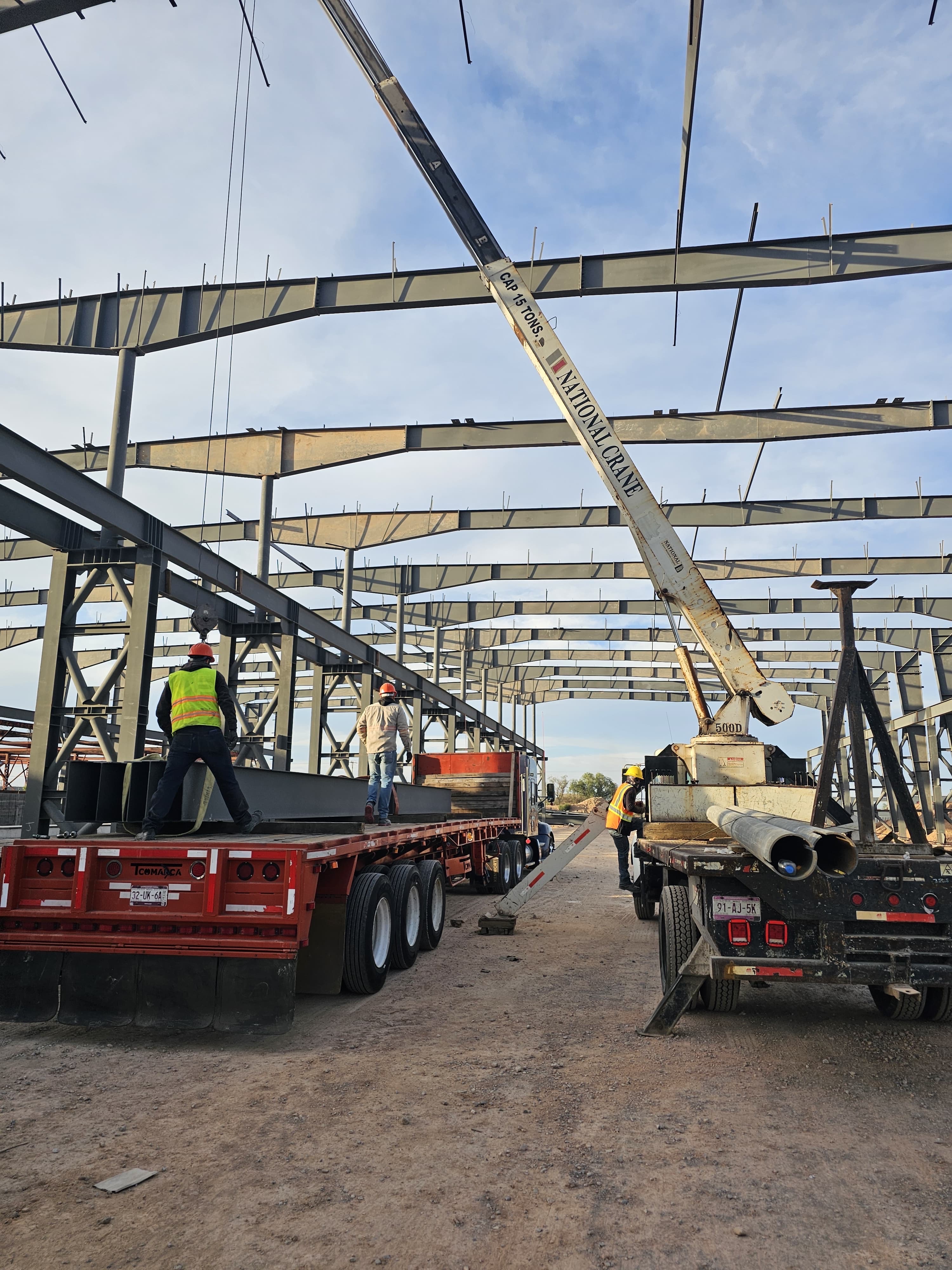 Construcción industrial con estructura metálica, grúa y operación de montaje