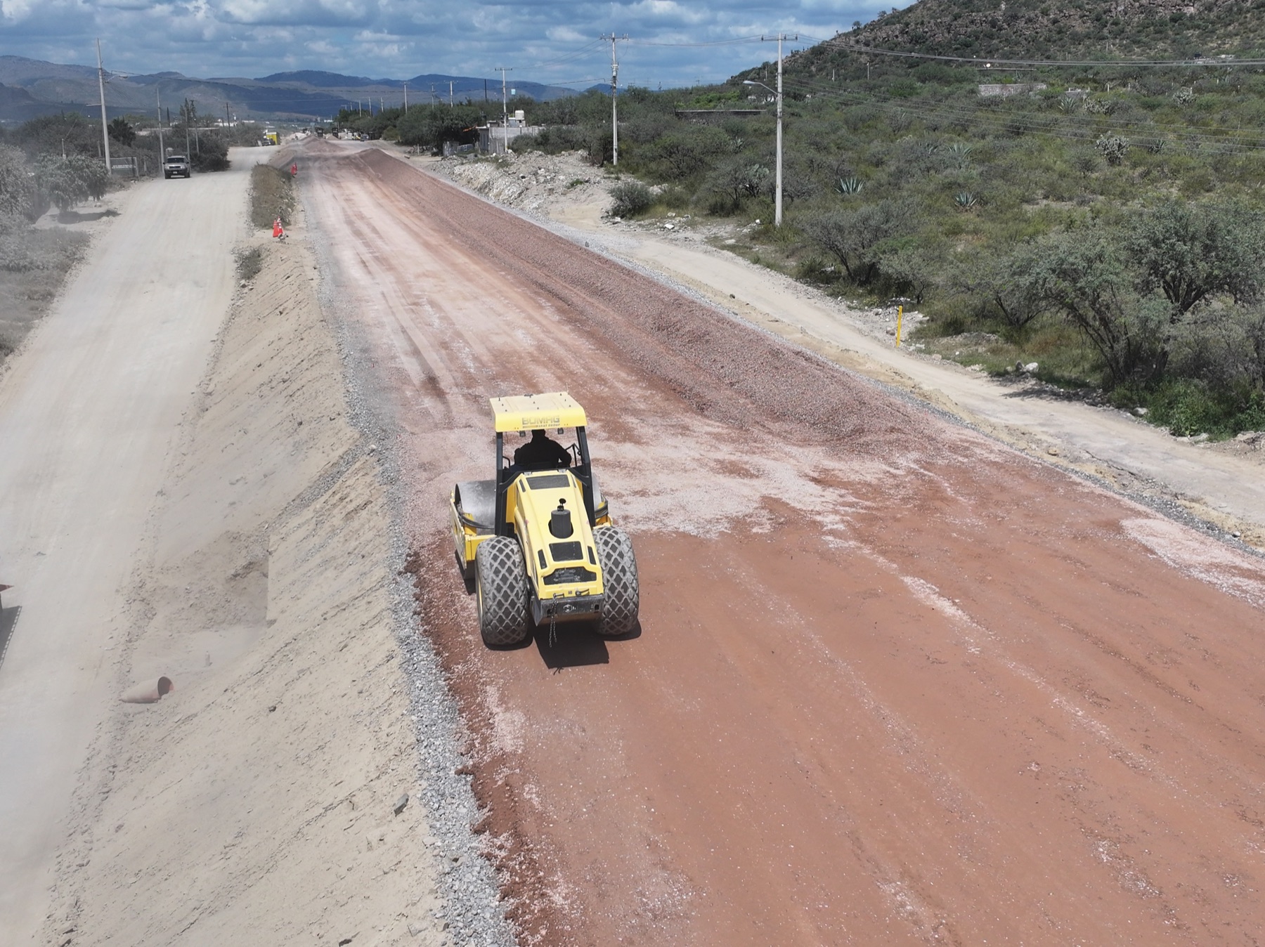 Camino en desarrollo con compactación y maquinaria en obra civil