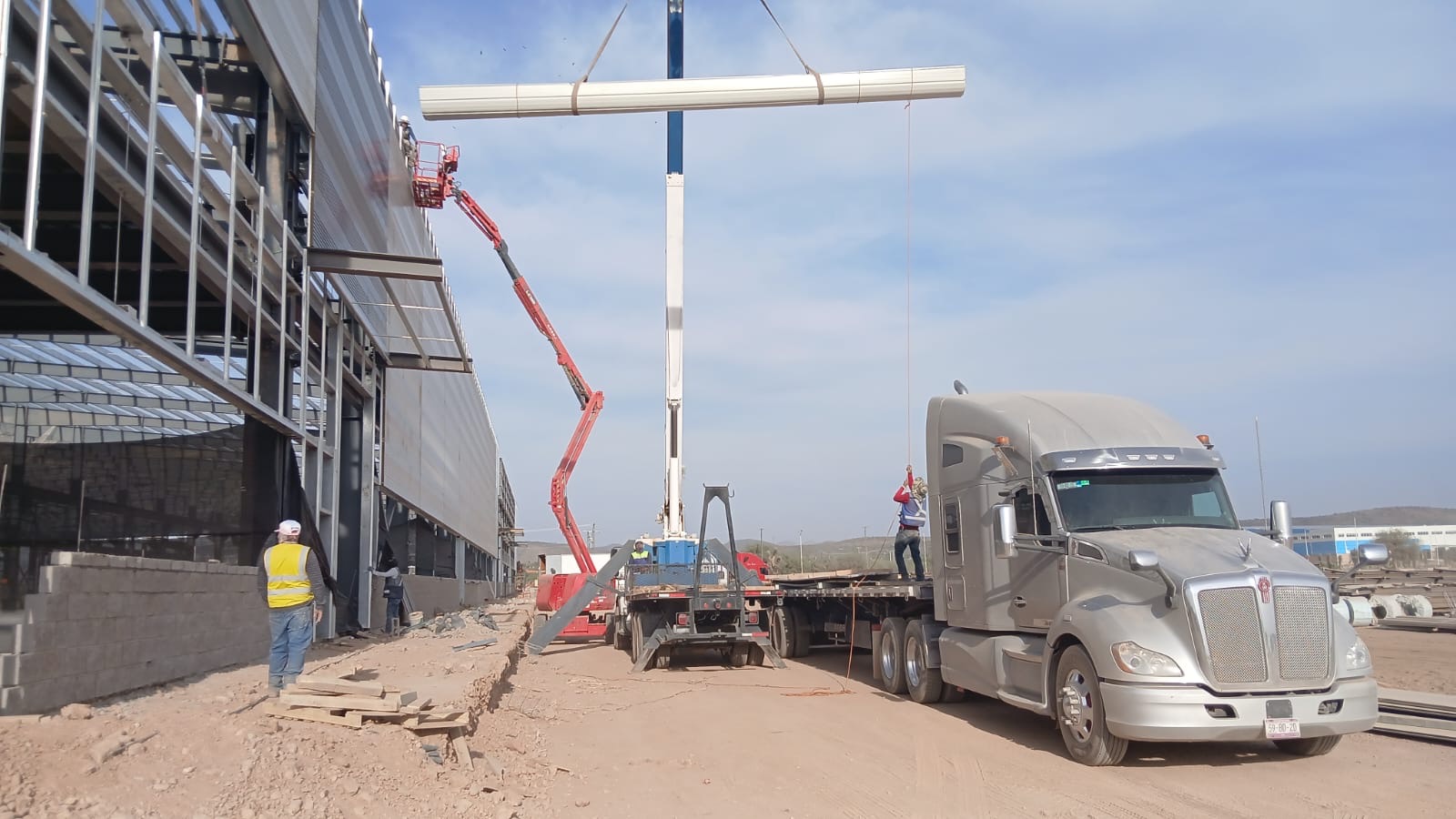 Obra exterior en proyecto comercial con grúa, camión y montaje de estructura
